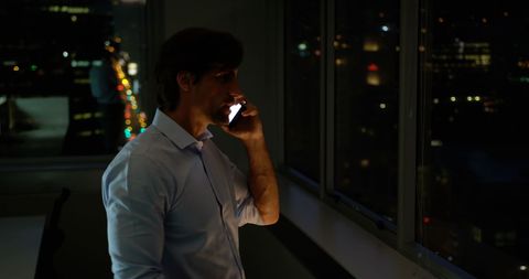 Executive speaking on mobile phone in night office