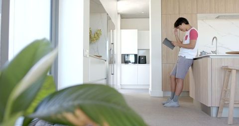 Young Man Studying on Tablet in Bright Modern Kitchen