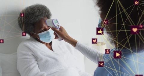 Nurse using infrared thermometer for temperature check on elderly patient
