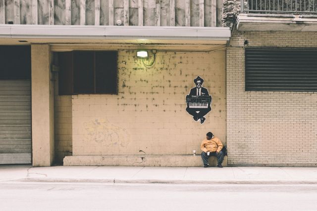 African american man sitting on the side of the street.