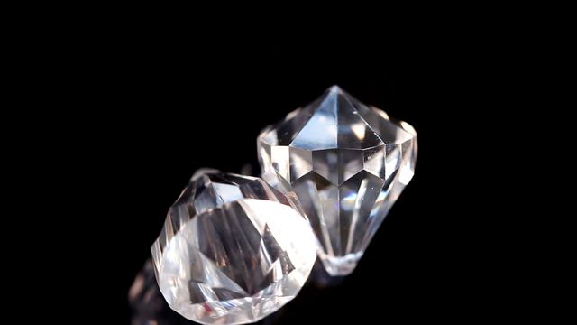 Close-up of two spinning diamonds in super slow motion, set against a black background. This can be used for advertisements related to luxury jewelry, fashion items, or high-end beauty products. It can also be used on e-commerce websites promoting luxury goods or incorporated into marketing materials for jewelry stores to highlight the quality and beauty of their products.