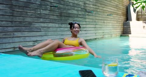 Woman Relaxing in Backyard Pool on Sunny Day
