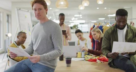 Design team reviewing fashion sketches in bright open-plan studio for apparel collection