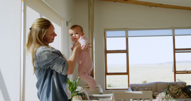 Smiling Mother Lifting Baby in Sunlit Living Room - Download Free Stock Images Pikwizard.com