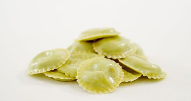 A pile of freshly made ravioli pasta is showcased against a white background, with copy space. Ravioli's distinctive shape and texture are highlighted, suggesting homemade Italian cuisine.
