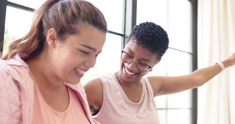 Laughing friends enjoying bright morning together in pastel activewear and eyeglasses
