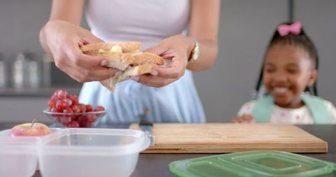 Mother preparing sandwich with daughter, family meal preparation activity