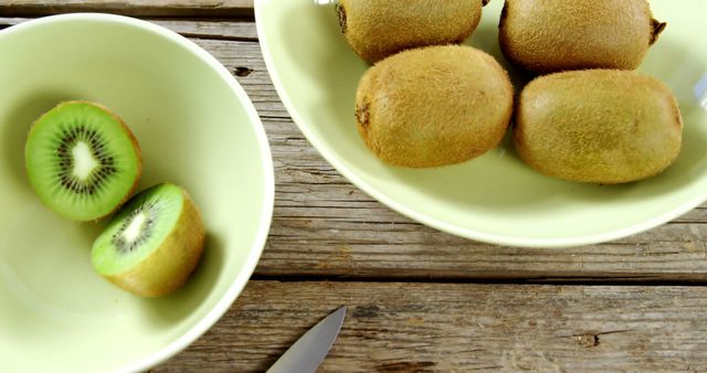Fresh kiwi fruits with one being cut on rustic wooden surface - Download Free Stock Images Pikwizard.com