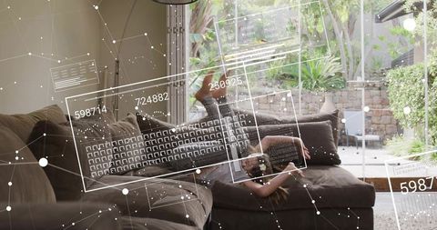 Child reclining on sectional sofa holding smartphone with augmented reality interface