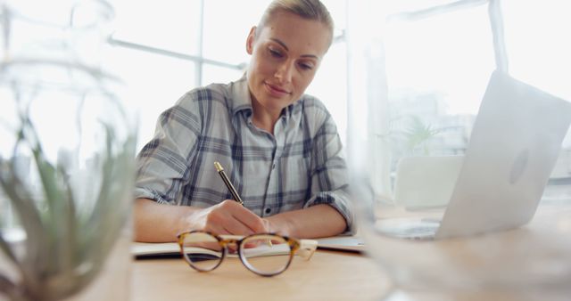 Focused Woman Writing Notes at Desk in Office - Download Free Stock Images Pikwizard.com