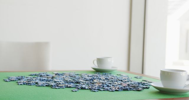 Image of puzzles and cups of coffee on green table. Retirement lifestyle, spending time together,active leisure time.