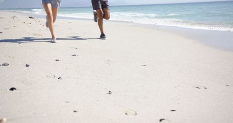 Beachside Joggers Creating Footprints in Sand