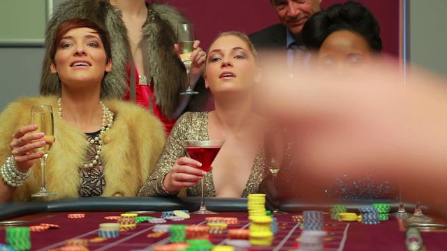 Video of three excited women celebrating a big win at a casino roulette table, holding drinks and surrounded by chips. Ideal for use in themes related to gambling, luck, nightlife, celebration, luxury lifestyle, and casino promotions.