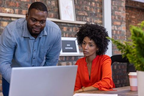 Colleagues Collaborating Over Laptop in Modern Office Setting