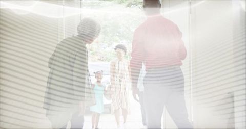 Multigenerational family greeting at sunlit front door, hugging on homecoming arrival