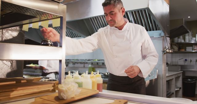 Chef wearing white uniform preparing meals in a professional restaurant kitchen. Image ideal for content related to culinary arts, professional chefs, food service industry, cooking techniques, and restaurant operations.