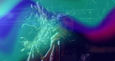 Dynamic Female Singer Performing Live Amidst Colorful Light Effects