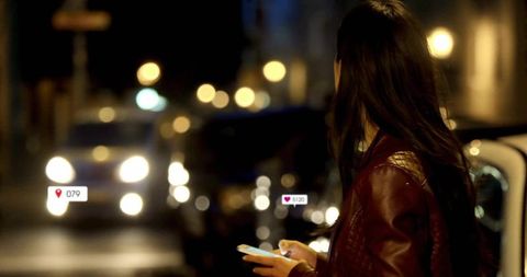 Young Woman Checking Phone on City Street at Night