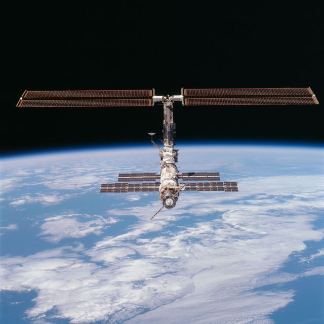 STS097-704-090 (9 December 2000) --- This picture of the distant International Space Station (ISS) blended against the darkness of space and the blue Earth at its horizon is one of a series of 70mm frames exposed of the station following undocking at 1:13 p.m.  (CST), December 9, 2000.  This series of images, as well as video and digital still imagery taken at the same time, represent the first imagery of the entire station with its new solar array panels deployed.  Before separation, the shuttle and space station had been docked to one another for 6 days, 23 hours and 13 minutes. Endeavour moved downward from the space station, then began a tail-first circle at a distance of about 500 feet. The maneuver, with pilot Michael J. Bloomfield at the controls, took about an hour.  While Endeavour flew that circle, the two spacecraft, moving at five miles a second, navigated about two-thirds of the way around the Earth. Undocking took place 235 statute miles above the border of Kazakhstan and China. When Endeavour made its final separation burn, the orbiter and the space station were near the northeastern coast of South America.