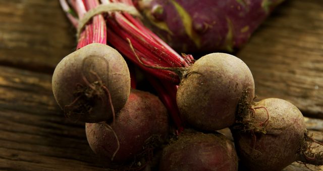 Close-up of organic beets tied together with rustic string, on wooden table. Can be used for promoting healthy eating, natural food lifestyle, vegetarian or vegan diets, farm-to-table concepts, fresh produce markets, nutritional blogs, and gardening magazines.