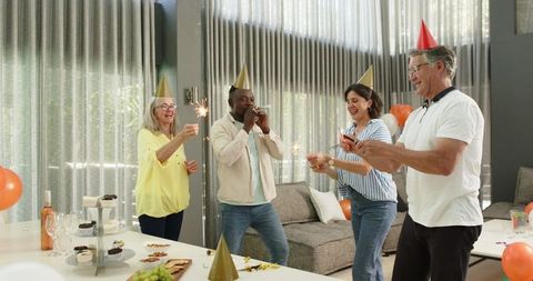 Colleagues celebrating with party hats and sparklers in office lounge