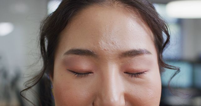 This closeup image of a young woman with her eyes closed shows her serene expression and highlights her natural makeup. Suitable for use in articles about beauty, skincare routines, and inner peace. Could be utilized in promotional material for cosmetic products, wellness blogs, or mental health resources.