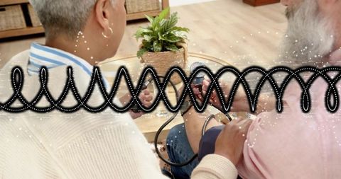 Mature couple checking blood pressure at home with portable cuff monitor and plant decor