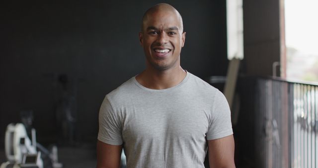 Portrait of happy biracial man wearing gray tshirt at gym. Activity, sport and exercise, unaltered.