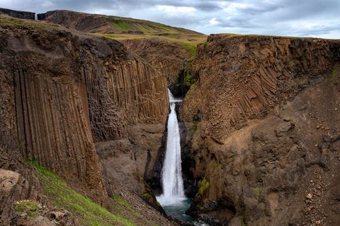 Waterfall Cascading Through Basalt Columns in Rugged Volcanic Canyon, Iceland