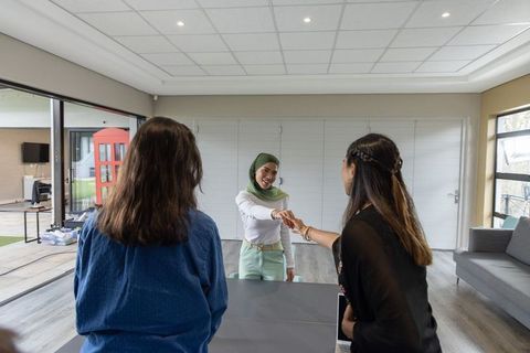 Diverse businesswomen shaking hands in modern meeting lounge, hijab professional greeting