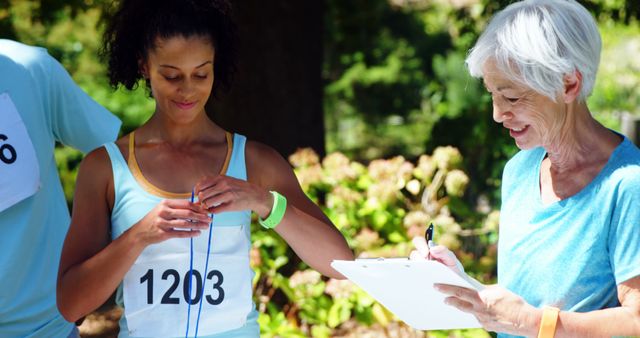 Female Jogger Adjusting Number While Senior Volunteer Making Notes - Download Free Stock Images Pikwizard.com