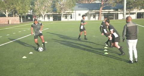 Soccer manager mentoring team during practice drill on field