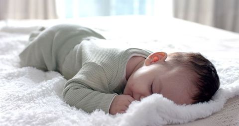 Infant Sleeping Peacefully on Plush Blanket in Sunlit Bedroom