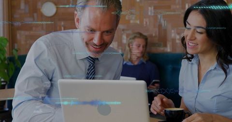 Smiling professionals collaborating over laptop in modern cafe with coffee and digital overlay