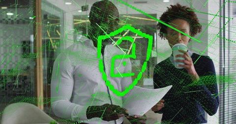 Collaborating over documents with neon cybersecurity shield overlay in modern office