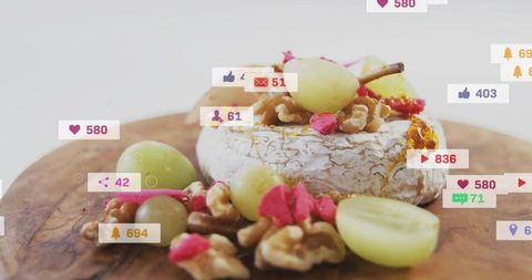Brie wheel topping with green grapes, walnuts, honey and social media engagement icons