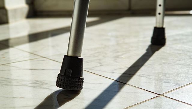 Walker legs casting long shadows on veined tile floor with rubber ferrules