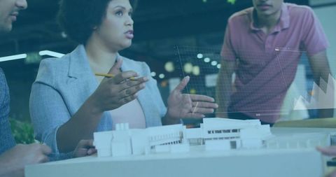 Architects discussing scale model with holographic data visualization for collaboration