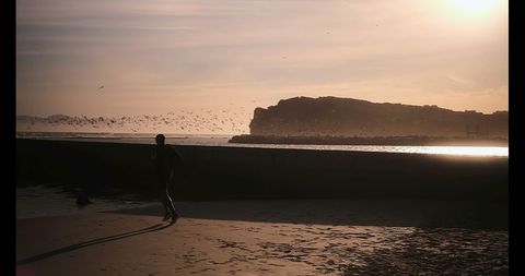 Young Male Running Along Seashore at Sunrise Silhouette - Download Free Stock Images Pikwizard.com