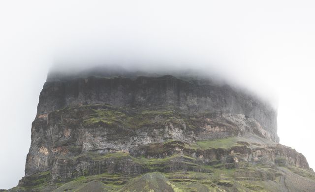 Majestic mountain peak shrouded in thick mist, capturing the essence of raw nature. Ideal for use in travel and adventure publications, inspirational posters, nature-themed promotional material, or background visuals for presentations that emphasize exploration and the great outdoors.