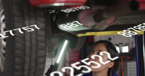 Female technician inspecting car undercarriage with led light and digital data overlay