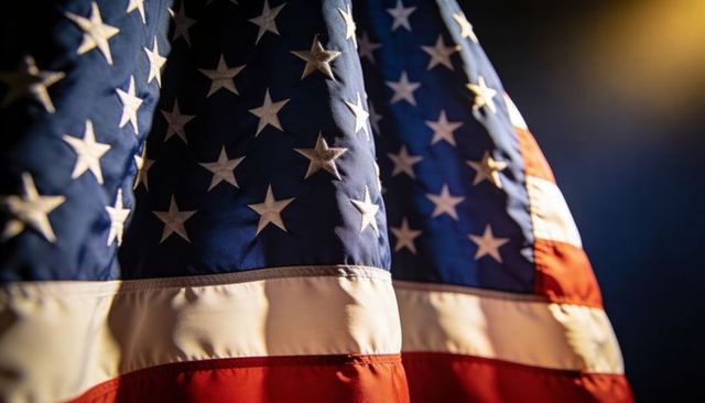 Closeup American flag waving, stitched stars and folded stripes glowing under warm light