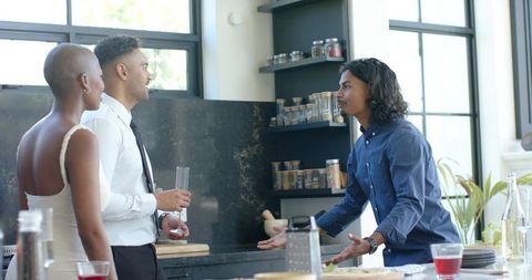 African american couple hosting friend in modern kitchen enjoying champagne toast