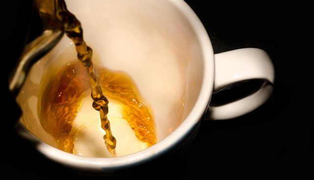 Close-up of steaming hot coffee being poured into a white mug set against a black background. Perfect for illustrating concepts related to morning routines, refreshing beverages, or coffee culture. Can be used in coffee shops advertising, morning routine blogs, or caffeine-themed content.