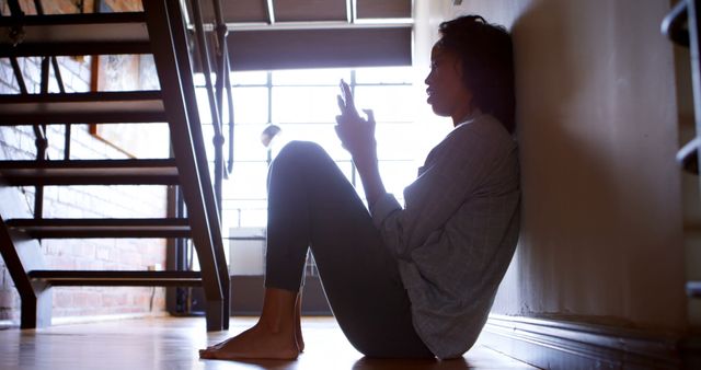 Woman using mobile phone while sitting on the floor at home 4k