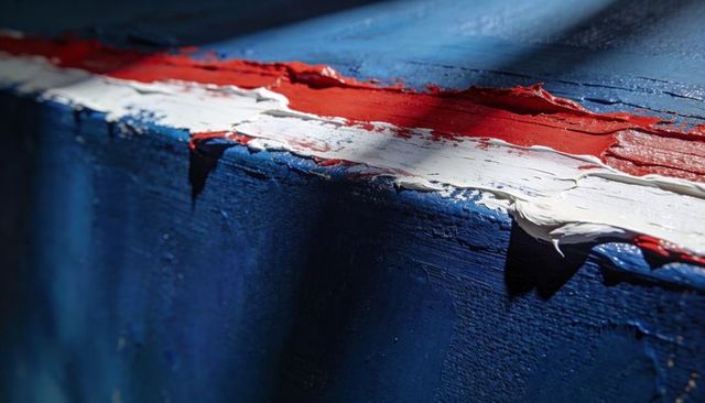 Macro detail of impasto paint edge showing red-white stripe on textured deep blue surface