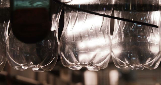 Close-up view of plastic bottles hanging upside down on a conveyer belt in an industrial setting. This can be used for articles and marketing related to manufacturing, industrial processes, automation, production, and packaging systems.