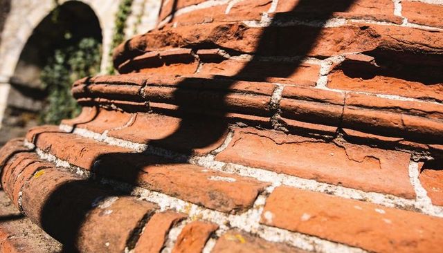 Sunlit weathered terracotta brick layers with white mortar and shadowed detail