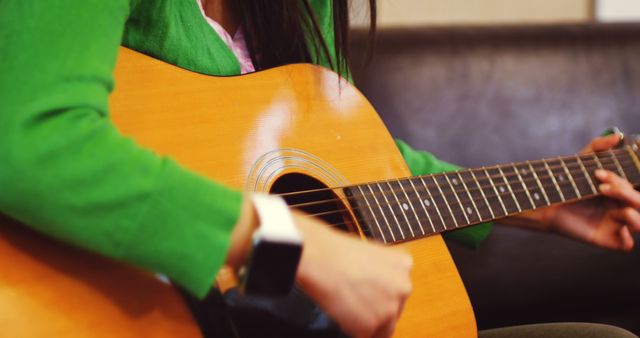 Woman playing guitar in living room at home