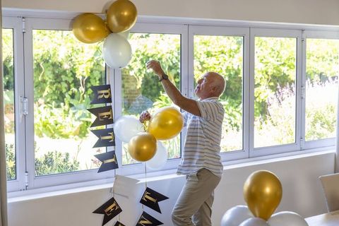Senior Man Celebrating Retirement at Home with Balloons